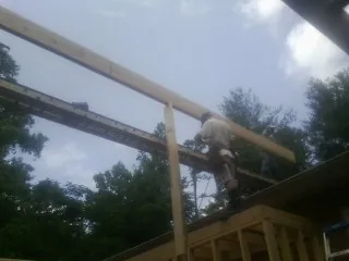 Carpenter setting a ridge beam over a new addition frame — Ice Dam Removal by Roofing Brothers in Madison Heights