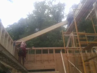 Carpenter raising a rafter beam on a new second story frame in Madison Heights