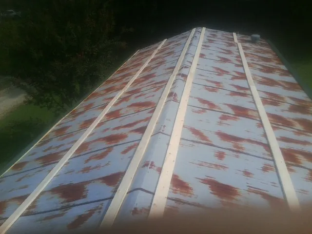 Rusted metal roof panels with new wood purlins before replacement — Storm Damage Roof Repair in Madison Heights by Roofing Brothers