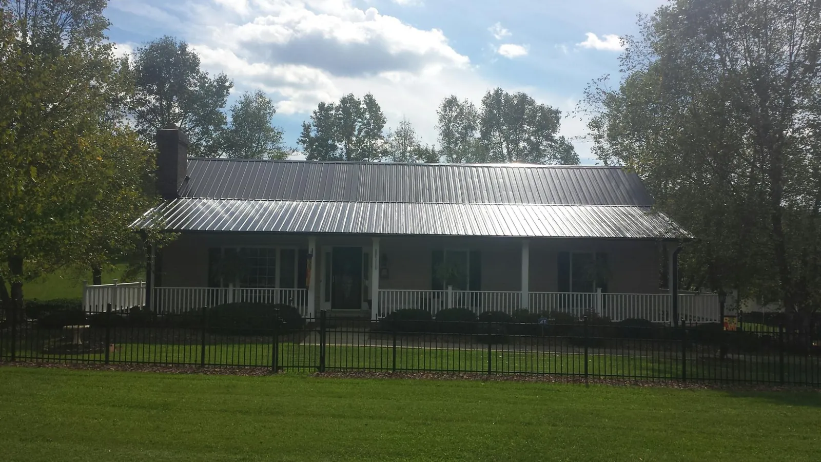 Gray metal roof on a brick ranch with a full width front porch — Gutter Guard Installation work by our crew in Madison Heights