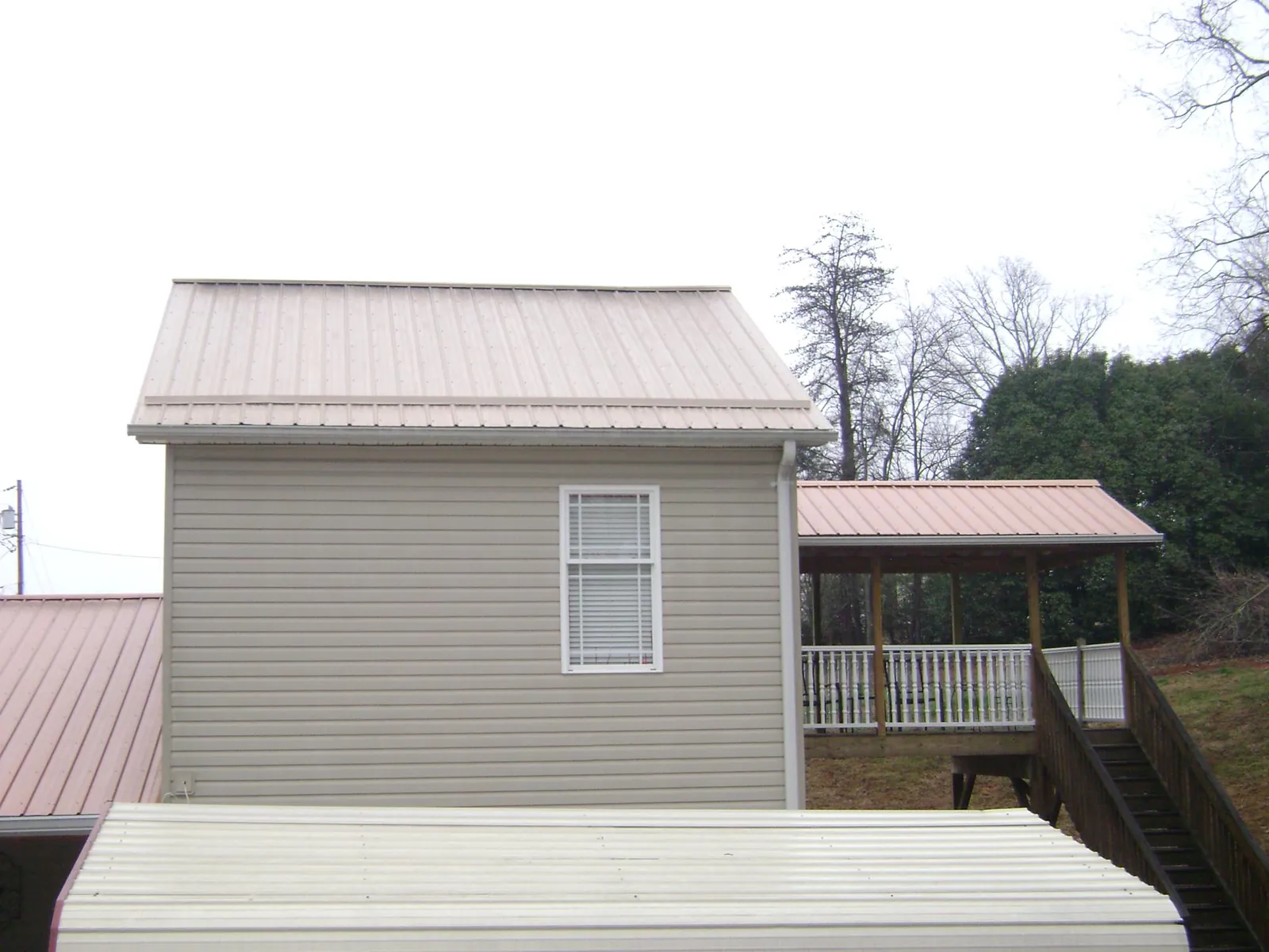 Tan metal roofs on a two story addition and attached porch, from a Roof Replacement job in Madison Heights